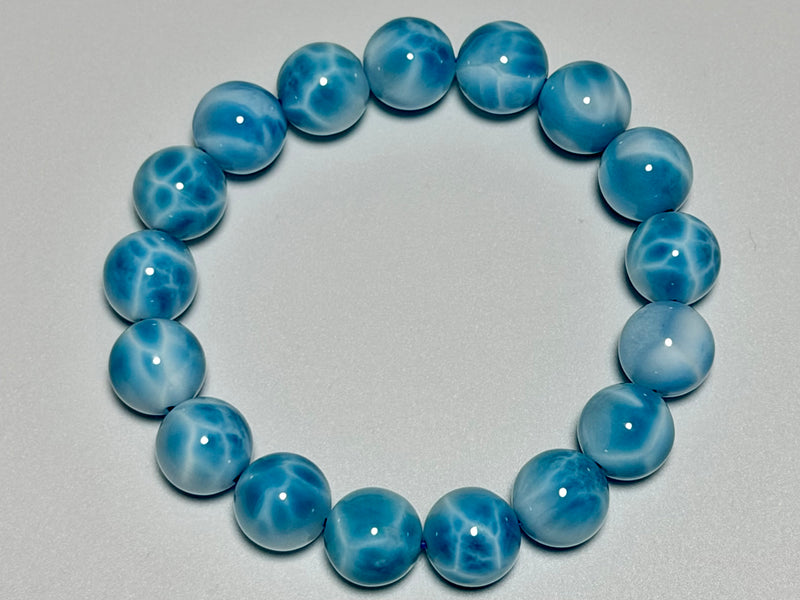 Larimar bracelet, 12 mm, top view showing blue color, white marbling, and bead arrangement.
