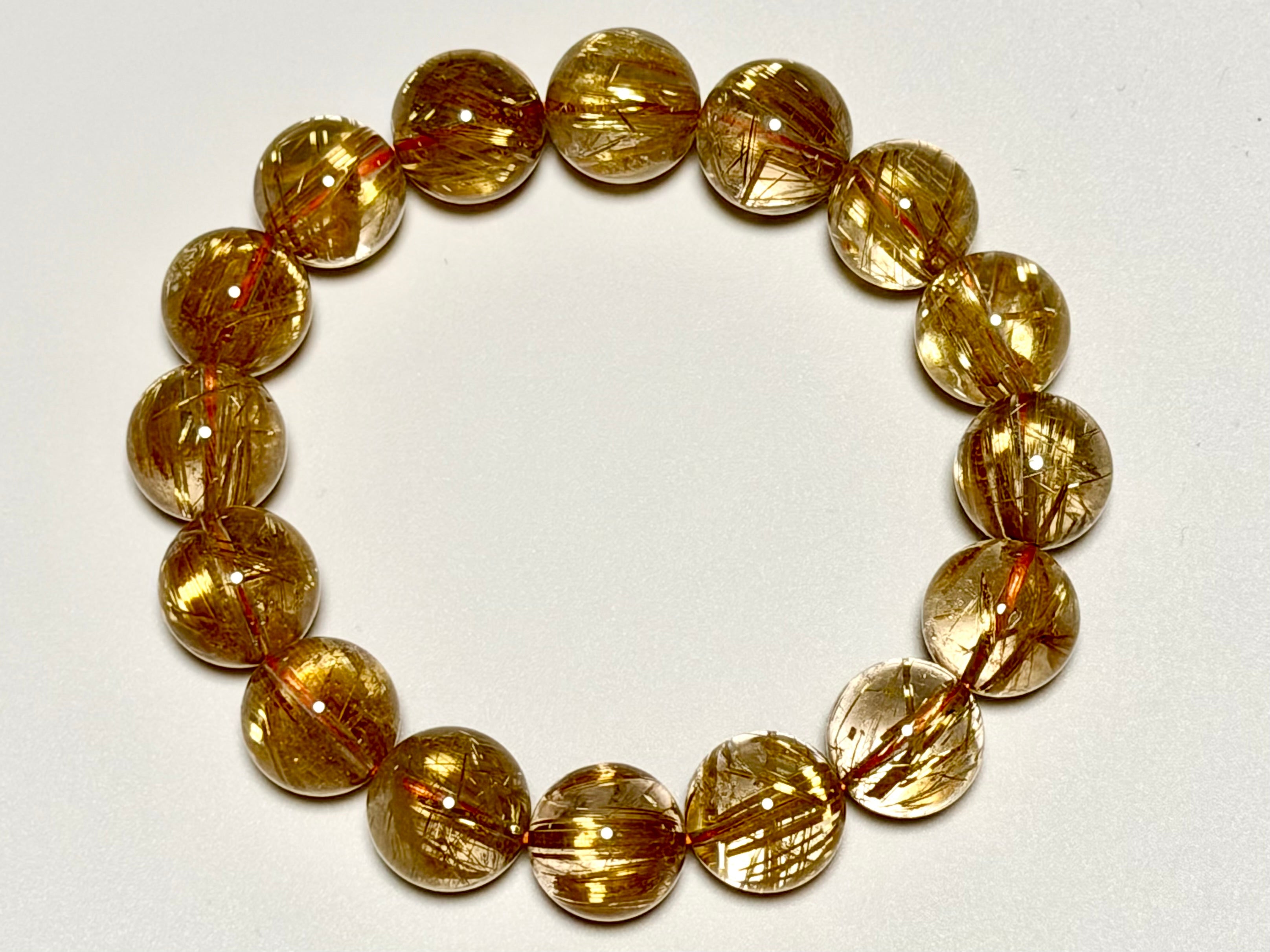 上から撮影したタイチンルチルクォーツ13-13.5mm。粒ごとの針の入り方、透明感、全体の配色バランスが確認できます。