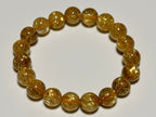 Taichin Golden Rutilated Quartz bracelet, 10 mm, thick-needle type, top view showing gold rutile needles, quartz translucency, and bead arrangement.