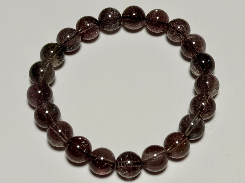 Hanabi Super Seven Quartz bracelet, 9–9.5 mm, top view showing reddish-purple inclusions and bead arrangement.
