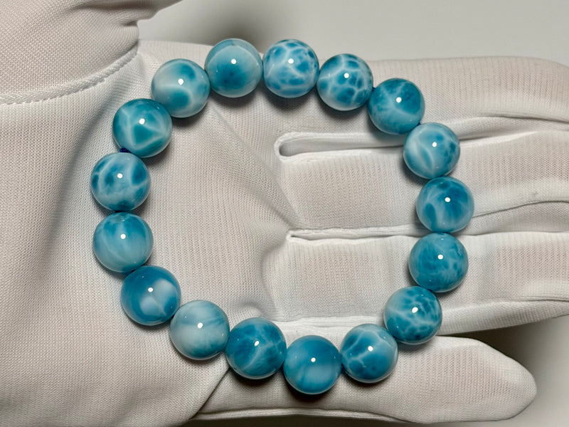 Larimar bracelet, 12 mm, gloved-hand view showing blue color and white marbling.