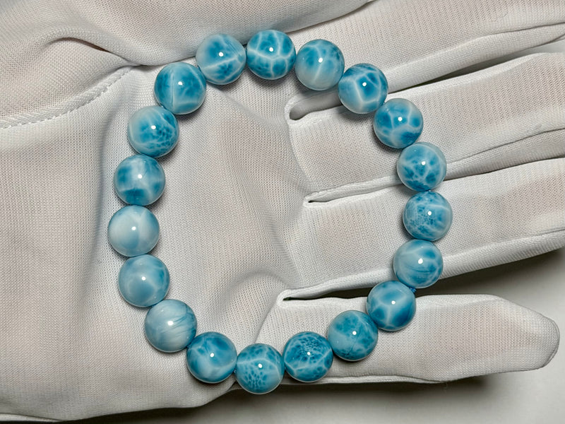 Larimar bracelet, 10.5–11 mm, gloved-hand view showing blue color and white marbling.