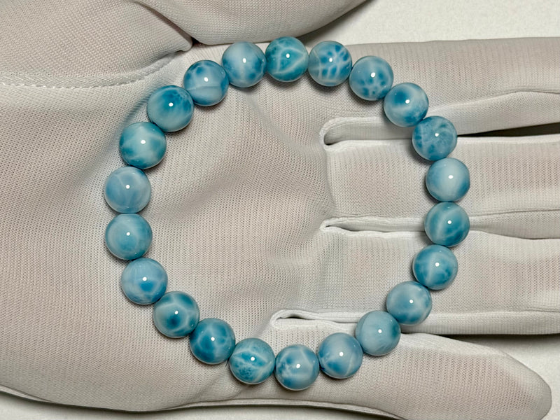 Larimar bracelet, 9.3 mm, gloved-hand view showing blue color and white marbling.