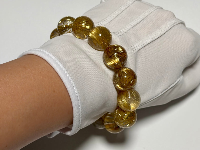 Taichin Golden Rutilated Quartz bracelet, 15–16 mm, angled view showing gold rutile needles and quartz translucency.
