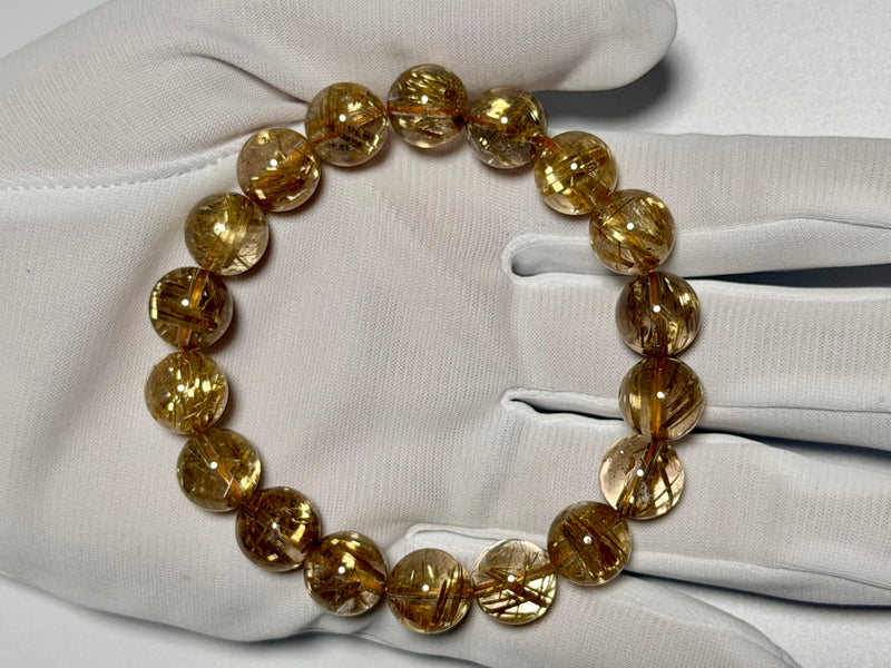 Taichin Golden Rutilated Quartz bracelet, 11.5 mm, gloved-hand view showing gold rutile needles.