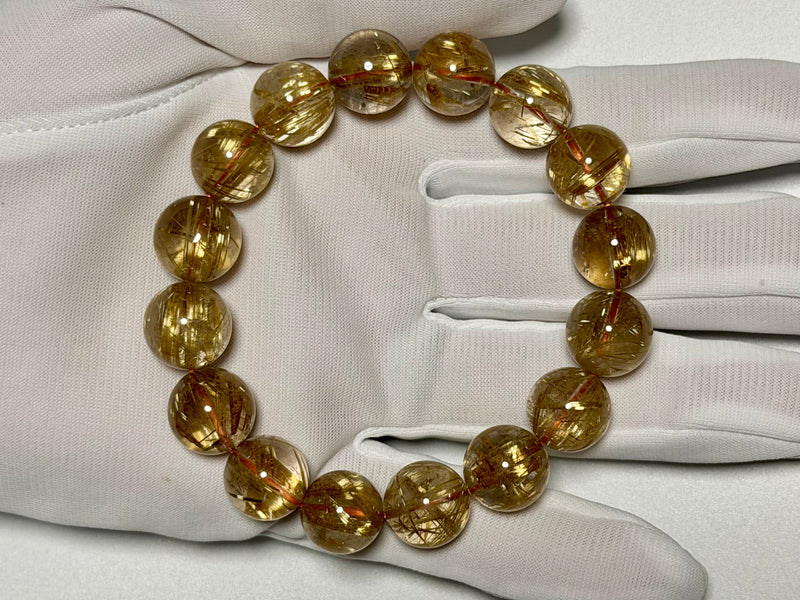 Taichin Golden Rutilated Quartz bracelet, 13–13.5 mm, gloved-hand view showing thick gold rutile needles.