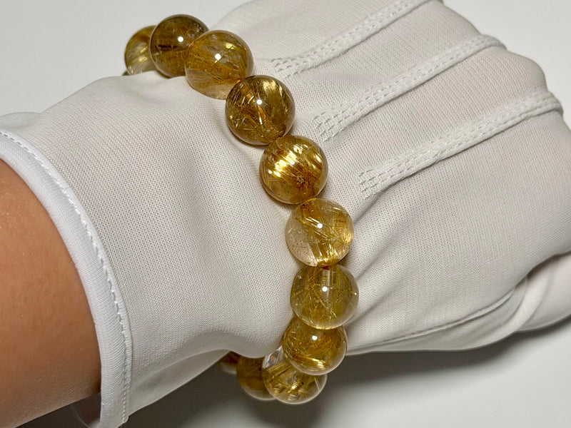 Rutilated Quartz bracelet, 13–13.5 mm, close-up showing gold rutile needles and quartz translucency.