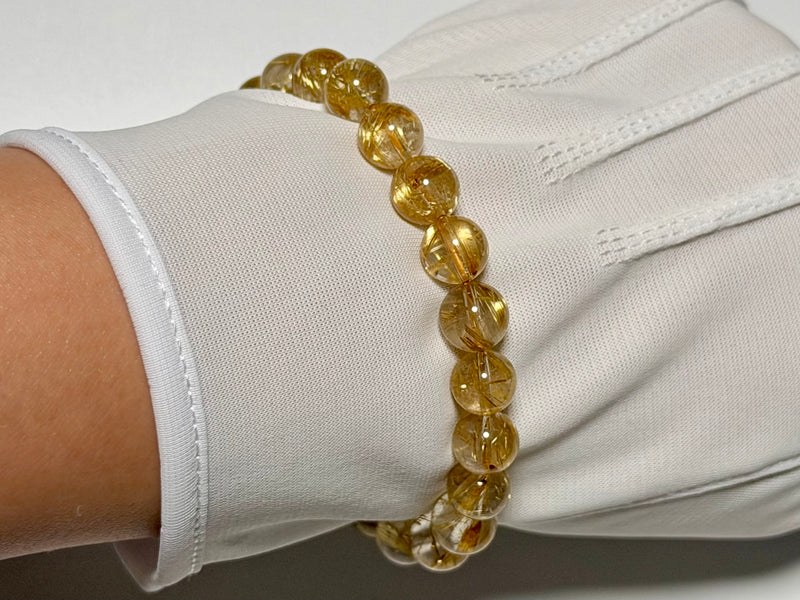 Taichin Golden Rutilated Quartz bracelet, 8.5 mm, angled view showing gold rutile needles and quartz translucency.
