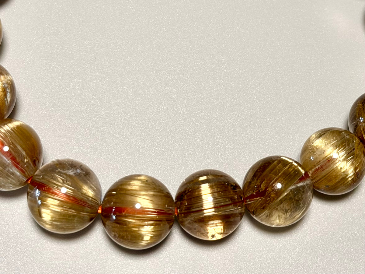 キャッツアイタイチンルチルクォーツ10mmのアップ写真。黄金針の密度、太い針と繊細な針の入り方、透明感を確認できます。