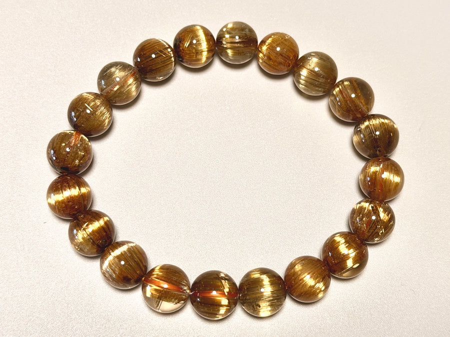 角度を変えて撮影したキャッツアイタイチンルチルクォーツ9.5-10mm。粒ごとの黄金針、キャッツアイ状の光、透明感を確認できます。